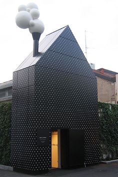 a black building with white polka dots on it and a light pole in the corner