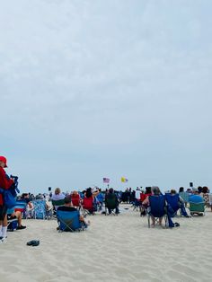 people are sitting in lawn chairs on the beach