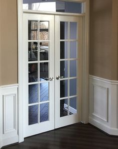 an empty room with french doors and hard wood flooring on the side walk way