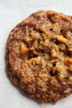 an oatmeal cookie sitting on top of a piece of white parchment paper