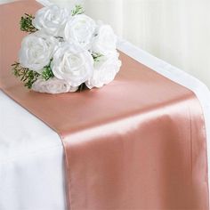 white flowers are placed on top of a pink table runner