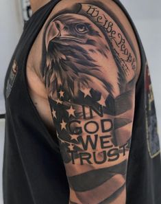 an eagle with the words in god we trust and american flag tattoo on his arm