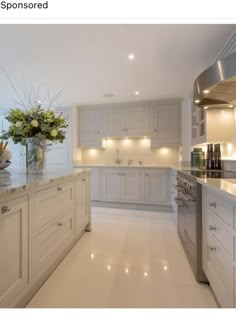 a large kitchen with white cabinets and marble counter tops