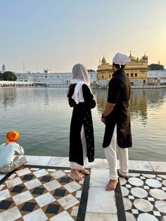 two people standing on the edge of a body of water