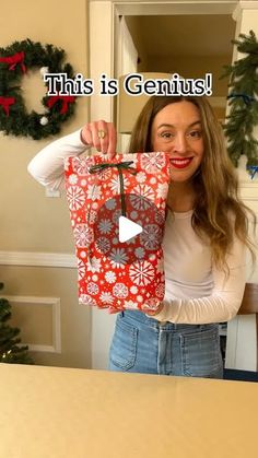 a woman holding up a christmas present in front of her face with the caption, this is genius