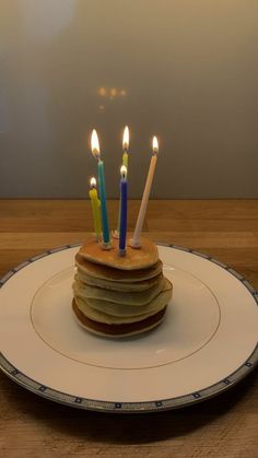 a stack of pancakes on a plate with lit candles sticking out of it's top