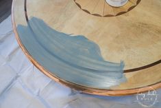 a round wooden table with blue paint on the top and brown trim around it's edges