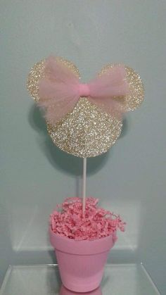 a pink and gold minnie mouse cake topper on a cupcake with glitter bow