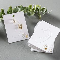 four cards with gold designs on them next to some flowers and greenery in the background