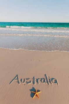 the word australia written in the sand with a starfish on it's side