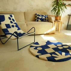 a living room with a couch, chair and rug on the floor next to a potted plant