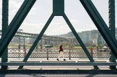 a woman walking across a bridge with buildings in the background