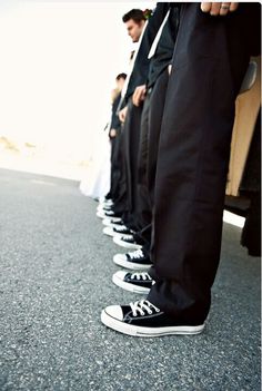 a line of people in black pants and white shoes standing next to each other with their hands on their hips