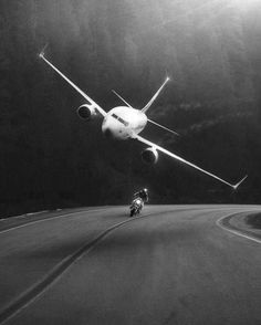 a black and white photo of a person riding a motorcycle in front of an airplane