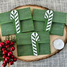 green and white christmas cards with candy canes on them sitting on a wood slice