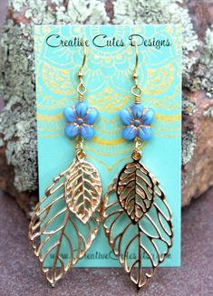 Lovely, large filigree gold leaves sway delicately from dainty blue Czech glass flower beads...Uniquely Charming! Uniquely hand crafted with these quality materials: ~ Gold plated filigree leaf charms ~ Czech glass blue pansy flower beads ~ Gold plated lead & nickel-free French style ear wires ~ Silicone earring backs to keep earrings securely in ears Measuring 3~1/4 inches from the top of the ear wires to the bottom of the leaves, they're light weight & sway delightfully! They will ship Gold Bohemian Leaf-shaped Jewelry, Bohemian Gold Leaf-shaped Jewelry, Bohemian Gold Leaf Jewelry, Bohemian Gold Flower Earrings, Bohemian Gold Flower Earrings Hypoallergenic, Gold Bohemian Flower Earrings Hypoallergenic, Bohemian Gold Flower Hypoallergenic Earrings, Blue Pansy Flower, Blue Pansy