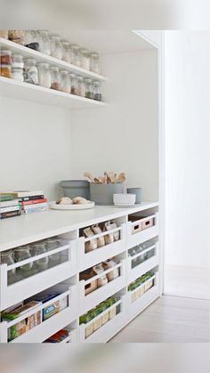 a kitchen with white cabinets and shelves filled with food