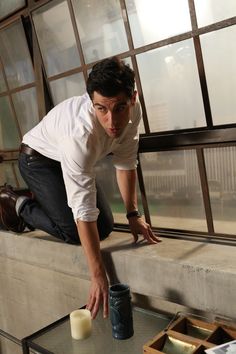 a man leaning down on a window sill with a candle in front of him