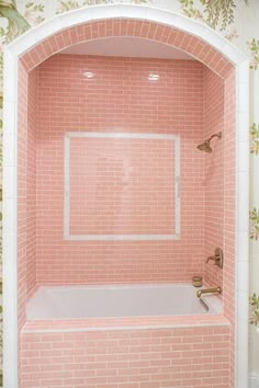 a bath tub sitting under a window next to a wallpapered wall with flowers on it