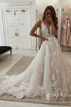 a woman taking a selfie in a wedding dress with white flowers on the skirt