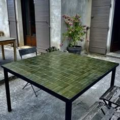 an outdoor table and chairs in front of a building with potted plants on it