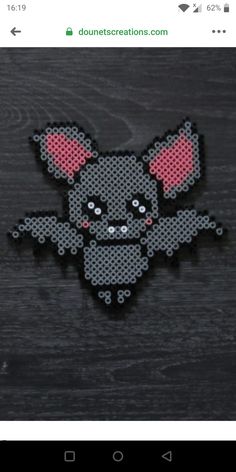 an embroidered patch with a cartoon mouse on it's face and ears, sitting on a wooden surface