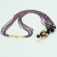 This gorgeous contemporary Murano necklace in rich amethyst and gold color palette features an exquisite 24K gold-layered heart at the center attached to a beautiful beaded ring and suspended from an elegant multi-strand beaded necklace. When this Venetian necklace captures the light you can really see it shine, as the seed beads and the heart light up with rich shades of amethyst, violet, and lilac reminding us of the treasures kept in Venice's decadent palazzos. This Murano glass necklace is a Elegant Single Strand Crystal Necklace Gift, Elegant Single Strand Crystal Necklace For Gift, Elegant Glass Beaded Jewelry, Elegant Beaded Glass Jewelry, Elegant Crystal Necklaces With Polished Beads, Elegant Long Purple Necklace, Elegant Glass Pendant Beaded Necklaces, Elegant Glass Pendant Beaded Necklace, Elegant Glass Beaded Pendant Necklace