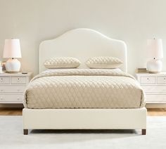 a white bed with two lamps on either side of the headboard and foot board