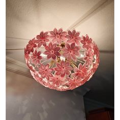 a pink ceiling light hanging from the ceiling with flowers on it's glass shade