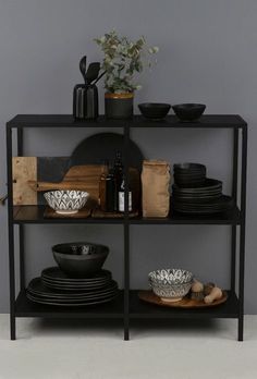 a black shelf with plates and bowls on it