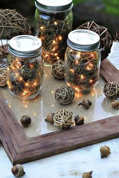 three mason jars with fairy lights in them sitting on a wooden tray surrounded by twine balls