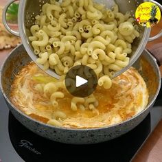 a pan filled with macaroni and cheese being stirred by a ladle on top of the stove