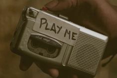 a person holding an old fashioned radio with play me written on the front and side