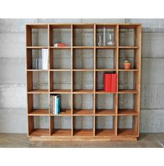 a wooden shelf with books and vases on it in front of a concrete wall