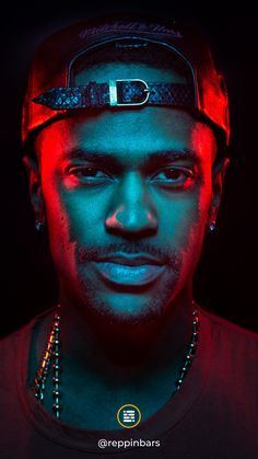 a man wearing a baseball cap and beaded necklace in front of a black background