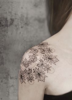 the back of a woman's shoulder with an intricate tattoo design on her arm