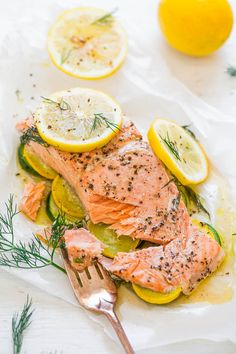 salmon with lemons, dill and herbs on parchment paper