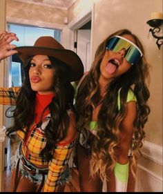 two young women dressed up in costumes and hats posing for the camera with their tongue out