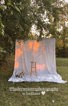 a chair sitting on top of a lush green field next to a white tarp