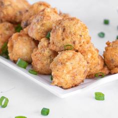 some fried food on a white plate with green onions and seasoning sprinkles