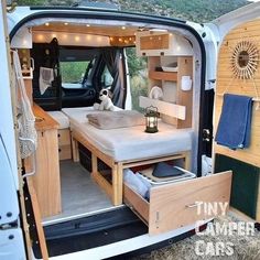 the interior of a camper van with its door open and bed in the back