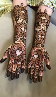 the hands are decorated with henna designs and hearts on their fingers, as if they were for someone's special occasion