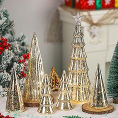 small christmas trees in gold and silver on a table next to other holiday decor items