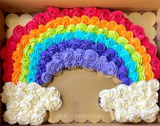 a rainbow shaped cake in a box with white frosting on the top and bottom