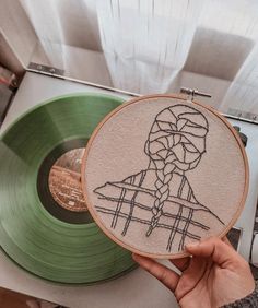 someone holding up a green record with a drawing on it