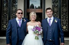 three men in suits and ties standing next to each other with flowers on their lapels