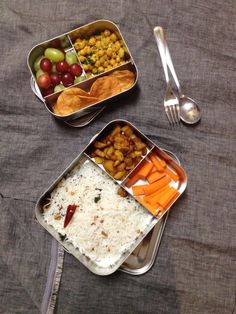 two metal trays filled with different types of food next to forks and spoons