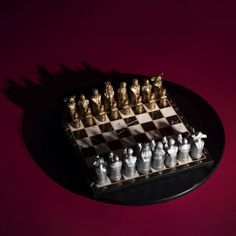 a chess board with gold and silver figures on it's side, against a red background