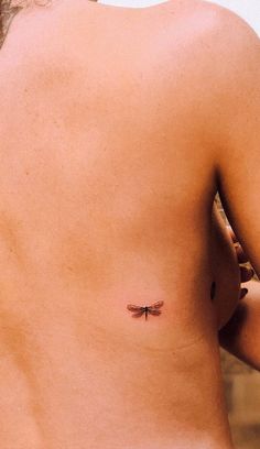 a woman with a small dragonfly tattoo on her back