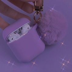 a person holding a purple case with a keychain attached to it and a furry ball hanging from the top